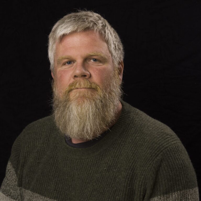 Image of Viggo Krüger, a male Norwegian music therapist with gray hair, a beard, and moustache, wearing a black and gray sweater