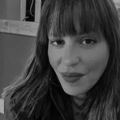 Music therapist, Hala Hamdan, who has dark, straight, shoulder-length hair, and is wearing a dark-colored jacket