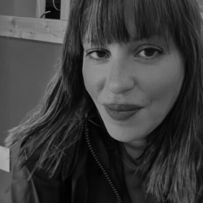 Music therapist, Hala Hamdan, who has dark, straight, shoulder-length hair, and is wearing a dark-colored jacket