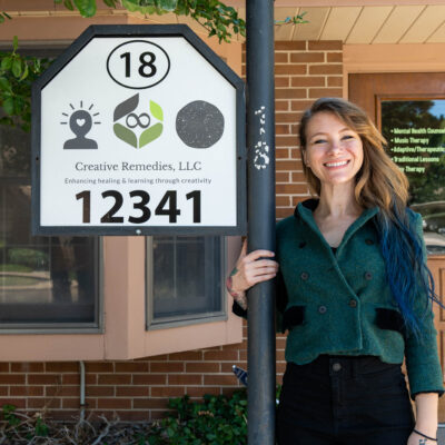 Music therapist and psychotherapist, Anastasia Canfield, who has long, straight hair, and is wearing a green blouse and black pants